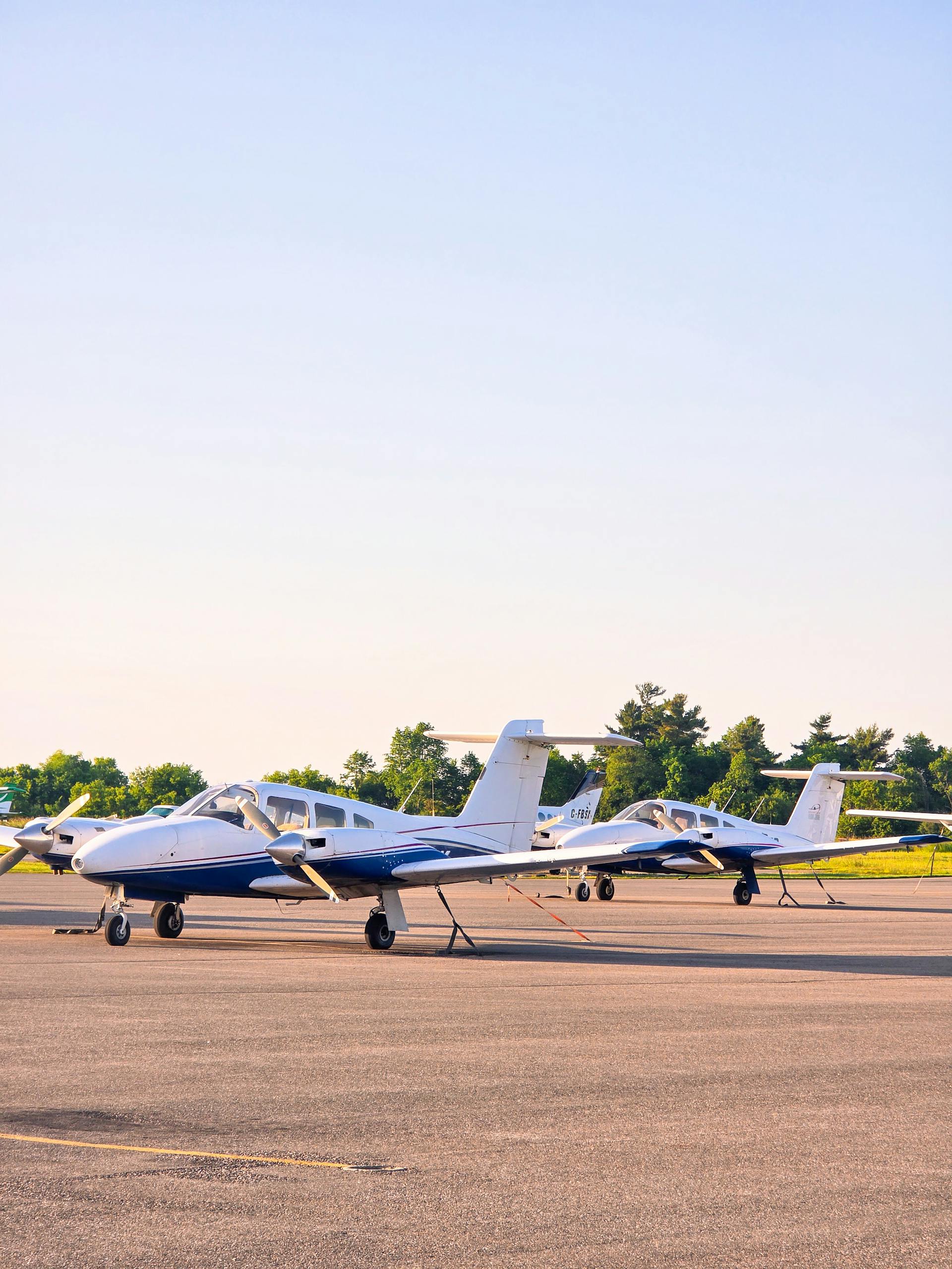 Two small private planes stationed outdoors on runway in Toronto, Ontario, captured on a sunny day.